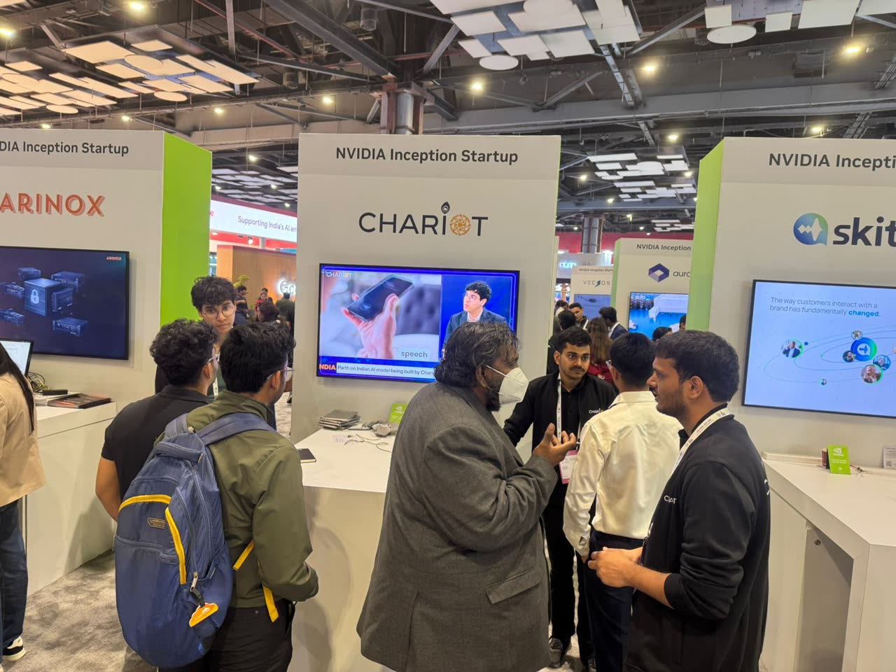 Visitors in conversation at the Chariot booth, with Parth's DD India interview playing on the screen